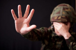 Soldier covering face suffering traumatic experience due to PTSD